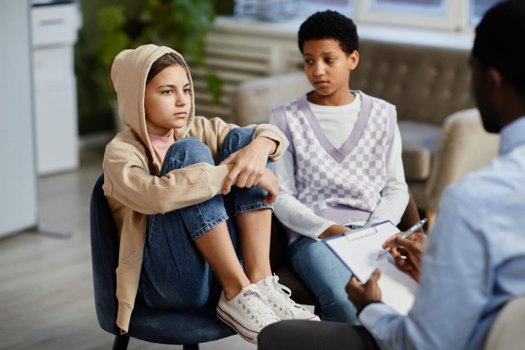 Teenage girl in group therapy session with diverse children